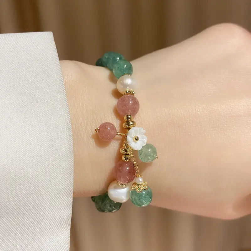 A delicate Korean floral green strawberry crystal beaded bracelet featuring a cascade of green pink and white beads with gold-toned accents and a central carved white flower charm.