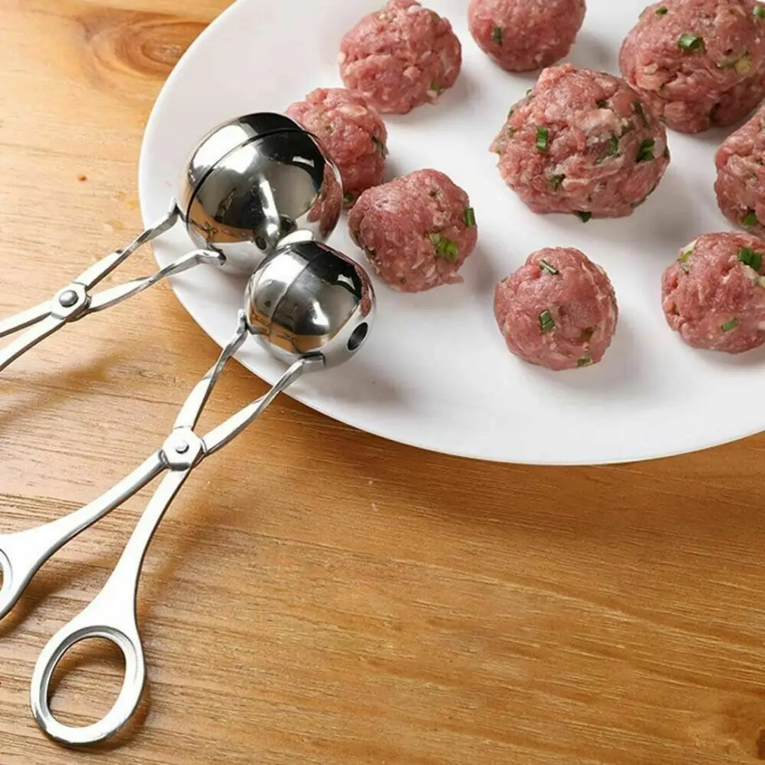 Stainless steel meatball maker tongs with shiny spherical scoops and ergonomic handles for kitchen use.