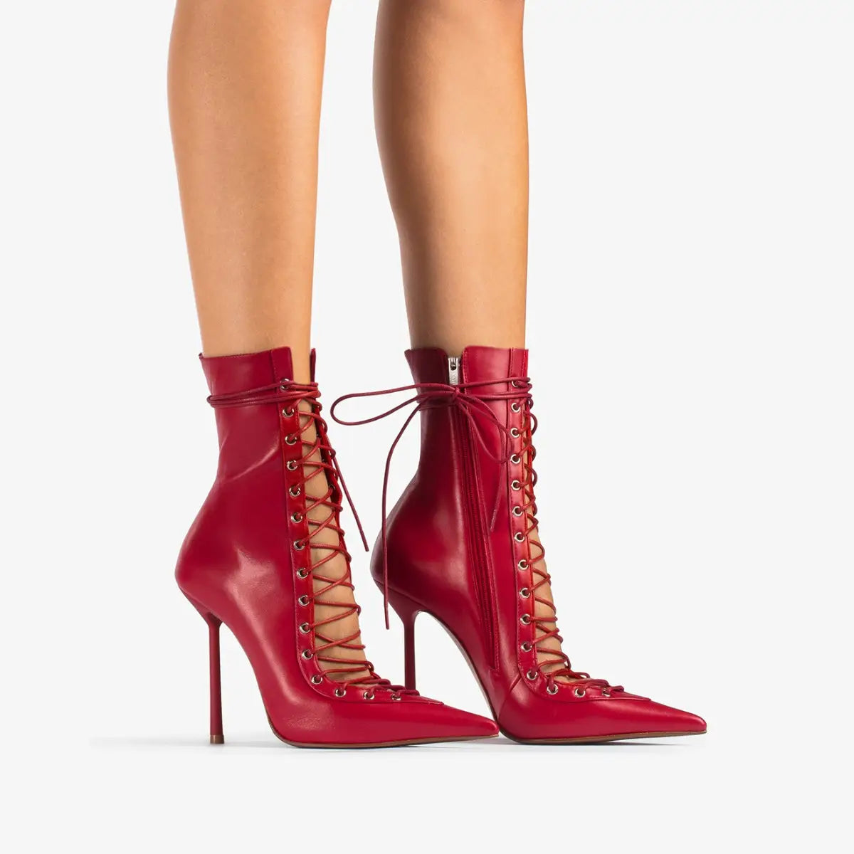 Des bottines à lacets en cuir verni rouge, à talon aiguille fin, présentées de l’arrière.