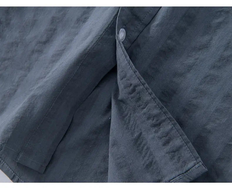 Dunkelgraues, leichtes Baumwollhemd mit dezenter Struktur und einem einzelnen weißen Knopf am Kragen, entworfen als gestreiftes kurzärmliges Casual-Shirt.