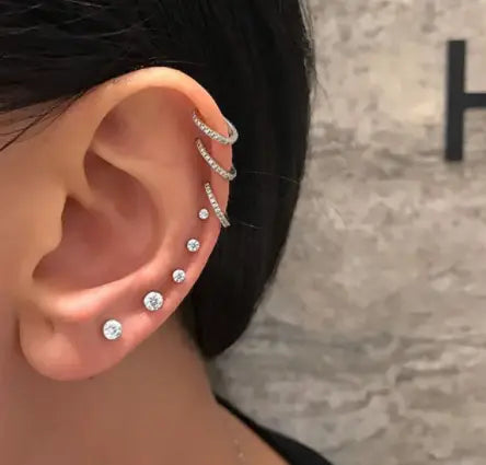 Silver hoop butterfly and diamond alloy ear cuffs with embedded diamonds worn stacked along the outer edge of the ear