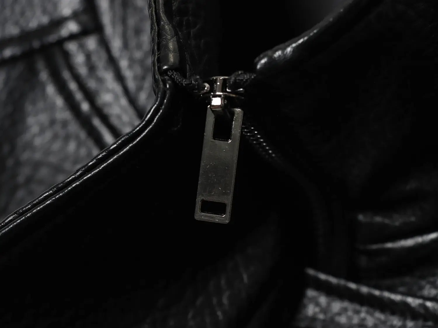 silberner Zipper-Schieber an einer schwarzen Damen-Motorradjacke mit hohem Stehkragen aus Kunstleder