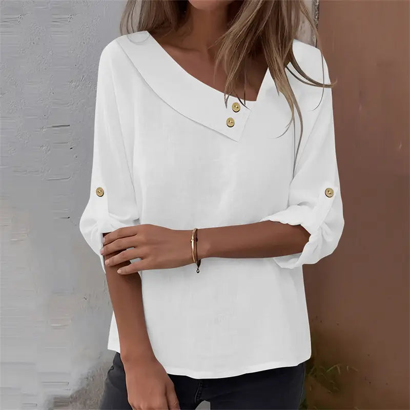 White asymmetric button blouse with v-neckline and gold-tone buttons at the collar and cuffs.