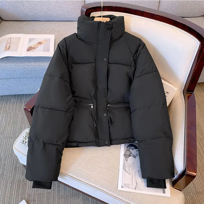 Chaqueta exterior de algodón acolchado para mujer en color negro, con cuello alto, cierre frontal con botones y dos bolsillos laterales.