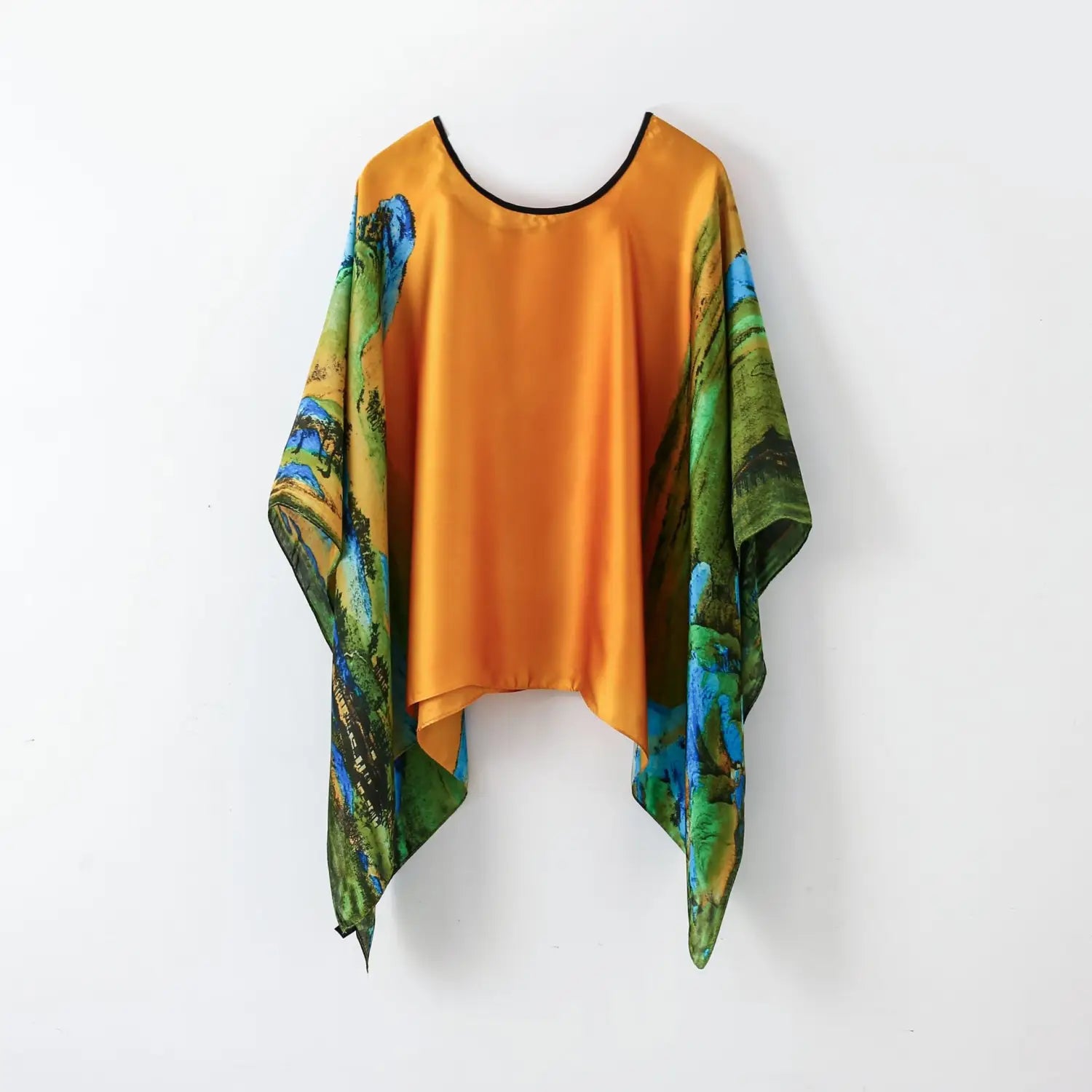 A vibrant orange printed silk patterned pullover shawl cape outerwear with a black-trimmed neckline and flowing sleeves featuring a vivid landscape print in greens, blues, and earthy tones.
