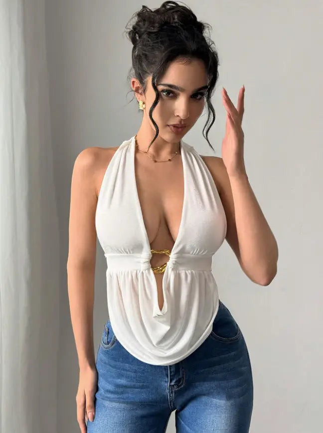 White halter neck top with a deep plunging neckline and gold-toned metal tie detail paired with black satin halter romper with faux leather shorts.