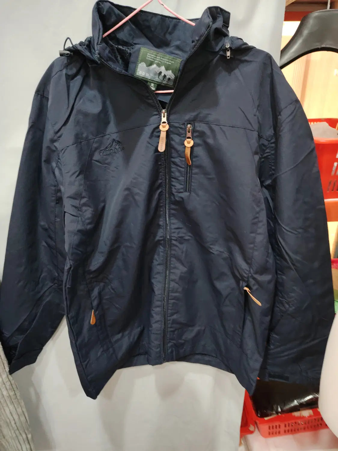 Chaqueta de senderismo con capucha impermeable color azul marino oscuro, con cierre frontal mediante cremallera y tiradores color cuero en las cremalleras.