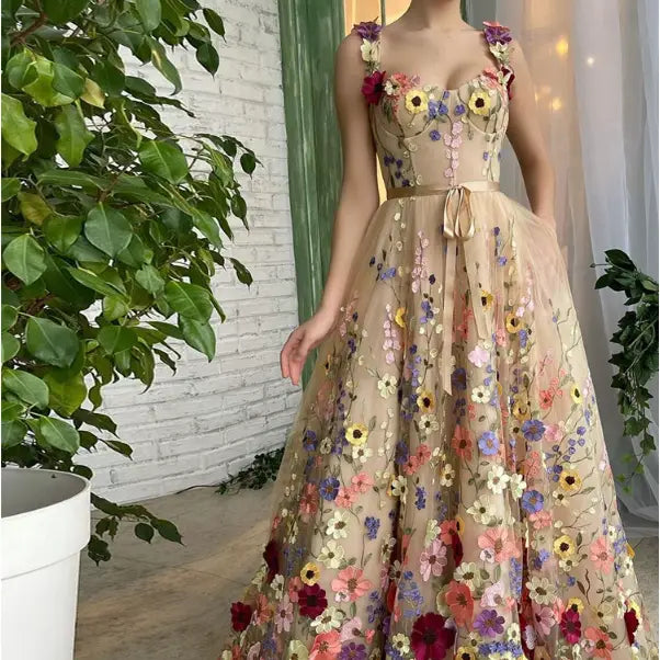 A flowing beige sweetheart tulle prom gown adorned with exquisite 3d floral embroidery in vibrant pink yellow purple and red hues.