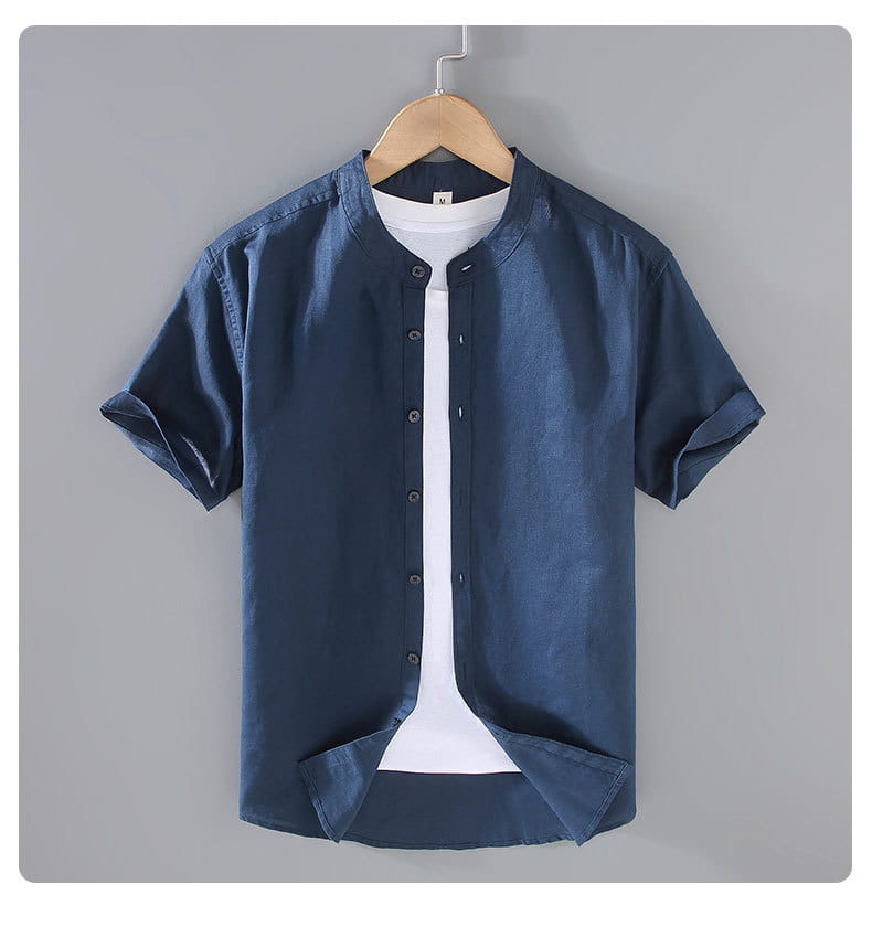 Dark blue men linen short-sleeved button-up shirt with mandarin collar hanging on a wooden hanger.