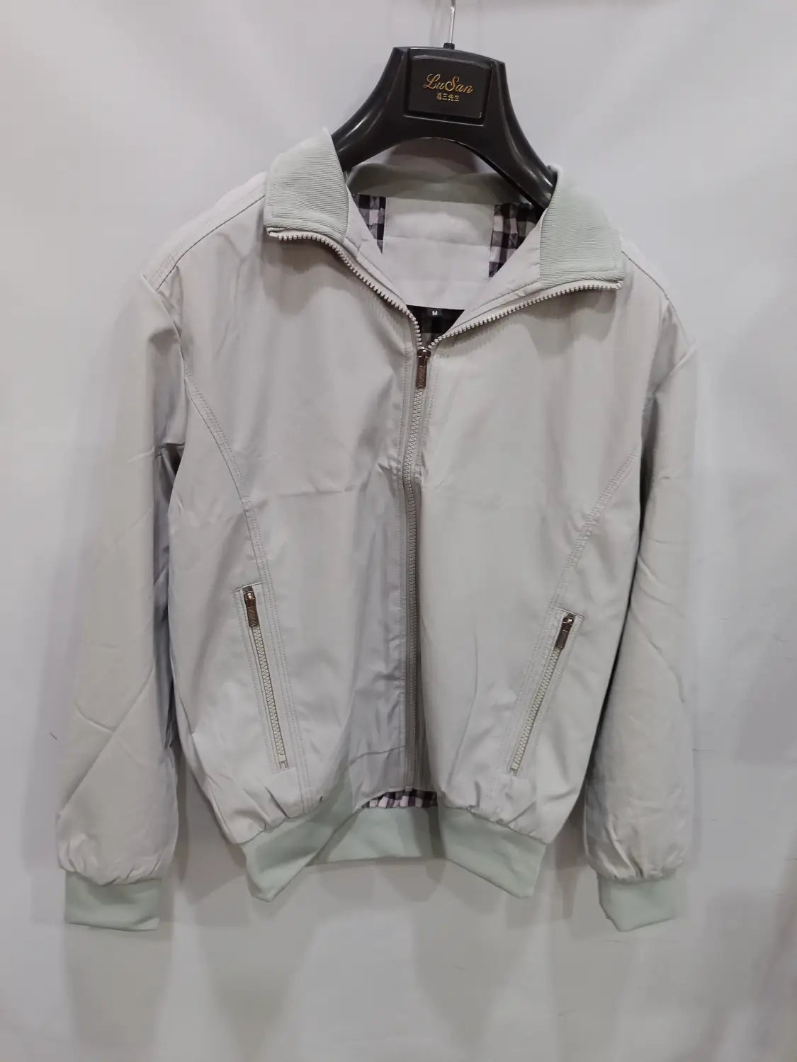 Veste bombardier légère pour homme en gris clair, avec fermetures éclair argentées à effet discret, poignets côtelés et doublure à carreaux