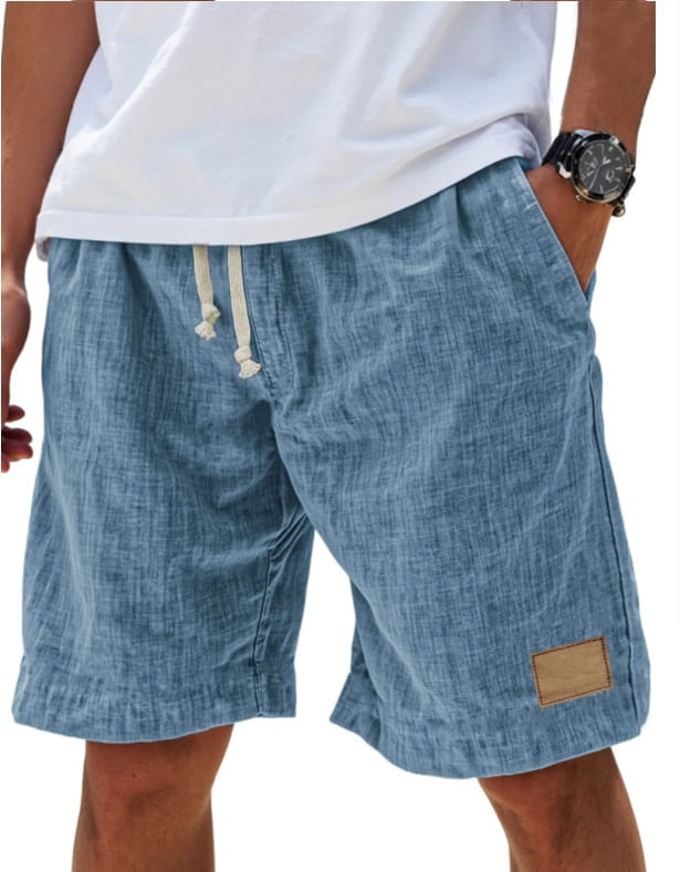 Light blue linen men holiday shorts with a drawstring waist and a small brown leather patch on the side designed for a breathable loose fit.