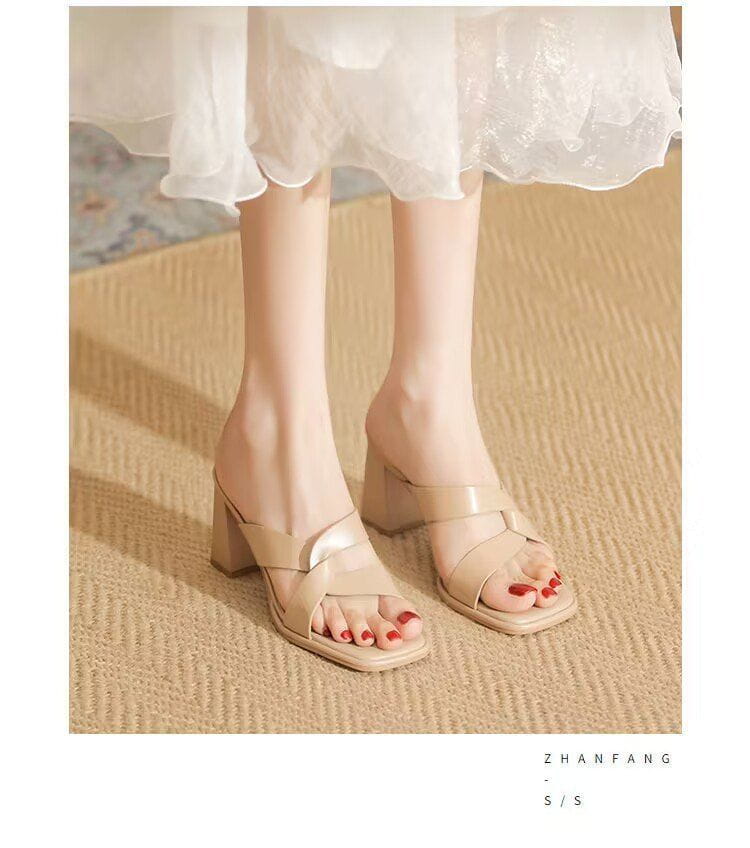 Beige leather-look chunky heel open toe sandals with crisscross straps and a subtle metallic accent on the strap featuring a sleek minimalist design.