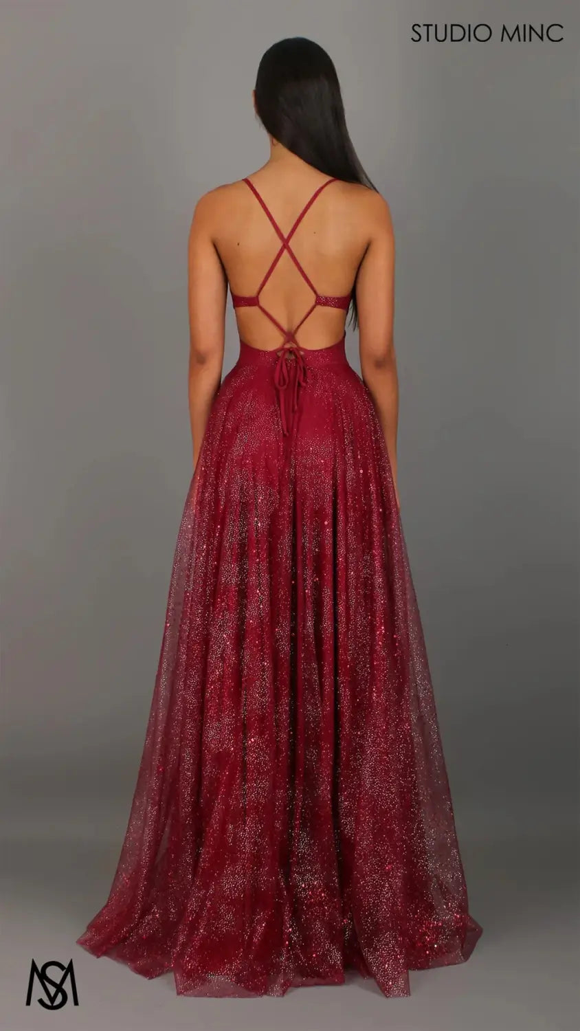 A shimmering burgundy v neck high slit maxi evening gown with sparkling textured fabric and an elegant crisscross back design shown from the back.