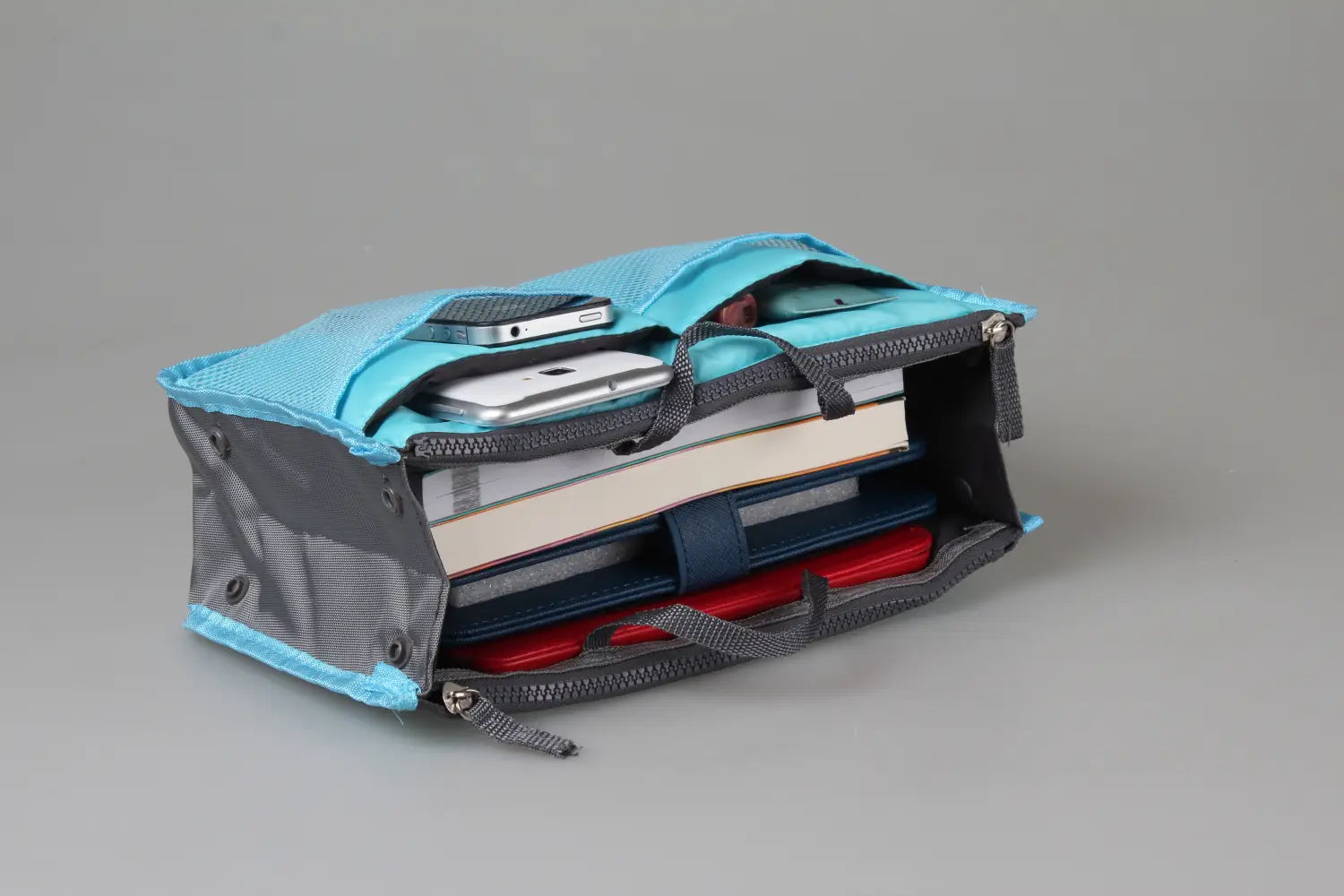 A teal and gray mesh multi-pocket nylon handbag organizer with dual zippered tops designed to hold phones books and other small items.
