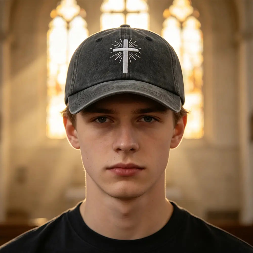 Casquette de baseball vintage délavée gris foncé, avec une croix blanche brodée et des lignes rayonnantes à l’avant.