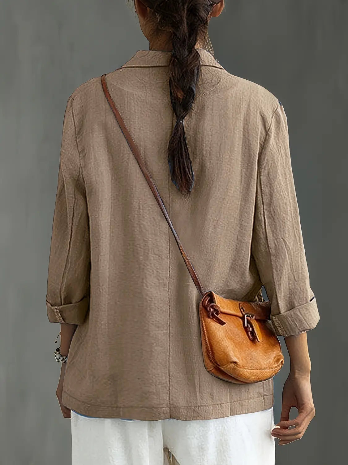 un bolso cruzado de cuero color camel con diseño vintage y correa marrón, combinado con un blazer de lino para mujer, casual y de trabajo