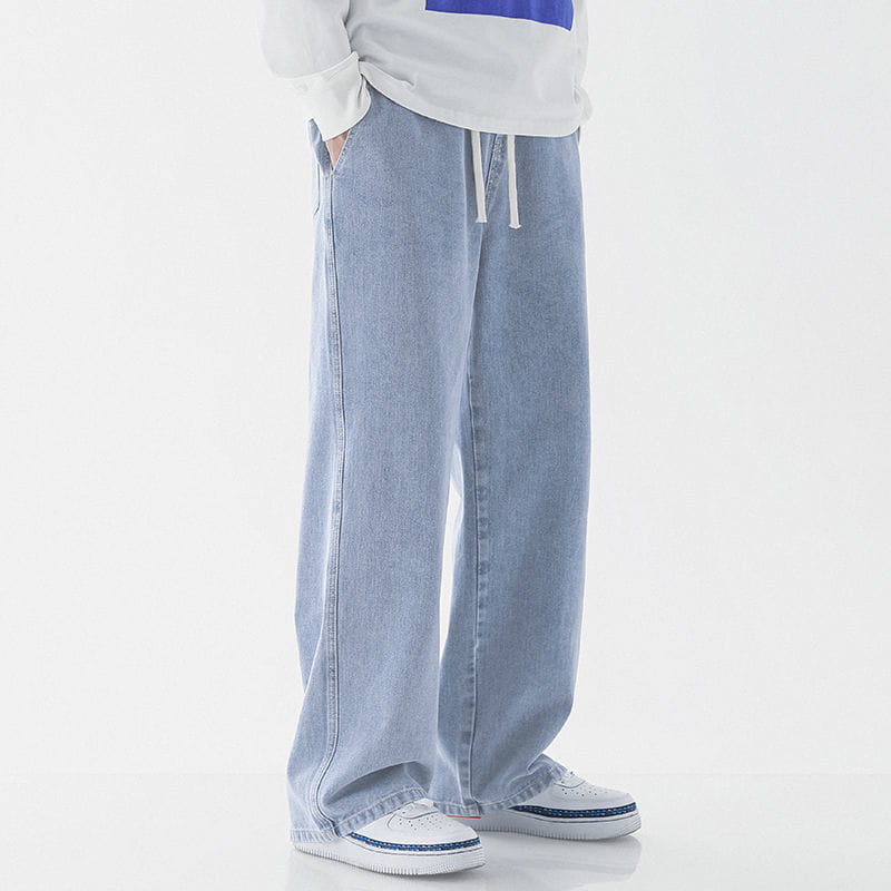 Men’s relaxed fit drawstring wide leg denim jeans in light wash with a relaxed fit and drawstring waist.