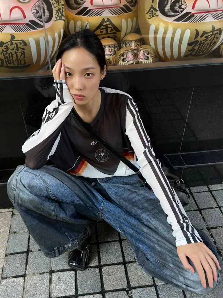 Schwarze und weiße langärmlige Sportjacke mit drei schwarzen Streifen auf jedem Ärmel, kombiniert mit Jeans mit Destroyed Wide-Leg im Vintage-Denim.