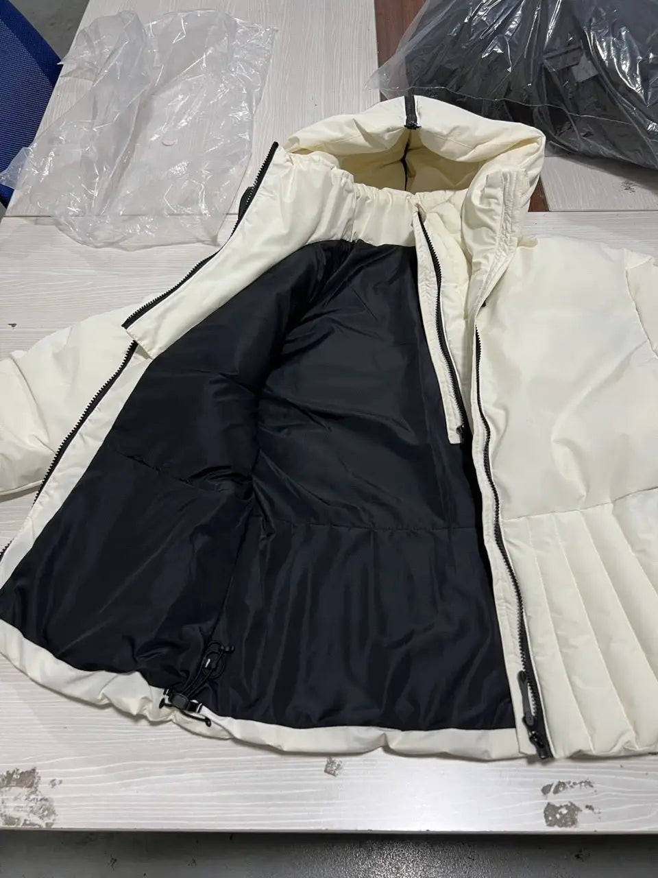 Cream-colored women’s belted hooded puffer coat with black interior lining and quilted design.