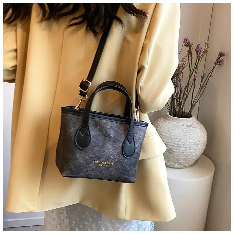 Black mini retro bucket bag with a subtle textured canvas pattern gold-tone hardware and matching black handles for shoulder use