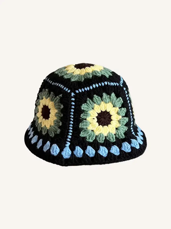 Un chapeau de pêcheur multicolore tricoté à la main, présentant une conception de seau au crochet noir fabriquée à la main, avec des motifs de tournesols jaune et vert éclatants, et une bordure bleue délicate le long du bord.