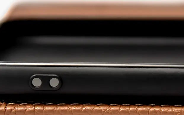black leather wallet case for iphone 16 15 14 13 12 11 showing the back side with dual camera cutout resting on a brown leather surface.