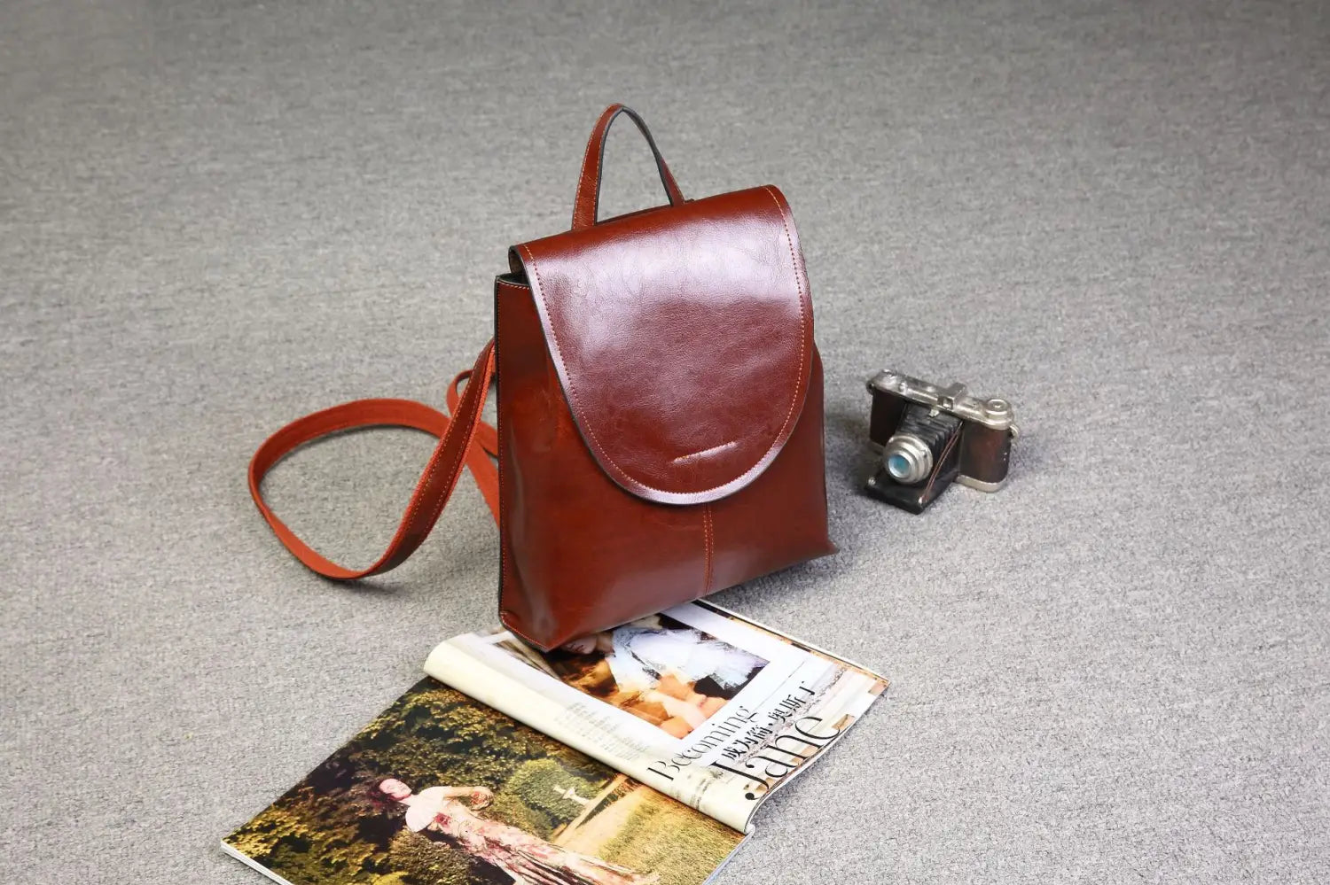 Una mochila bandolera de cuero marrón intenso con un diseño sencillo y minimalista y un único asa superior, adecuada para el uso en moda retro.