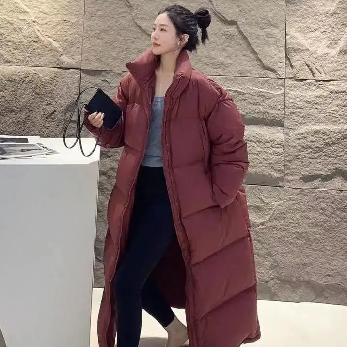 A long maroon quilted puffer coat for women made of cotton designed for winter wear with a high collar.
