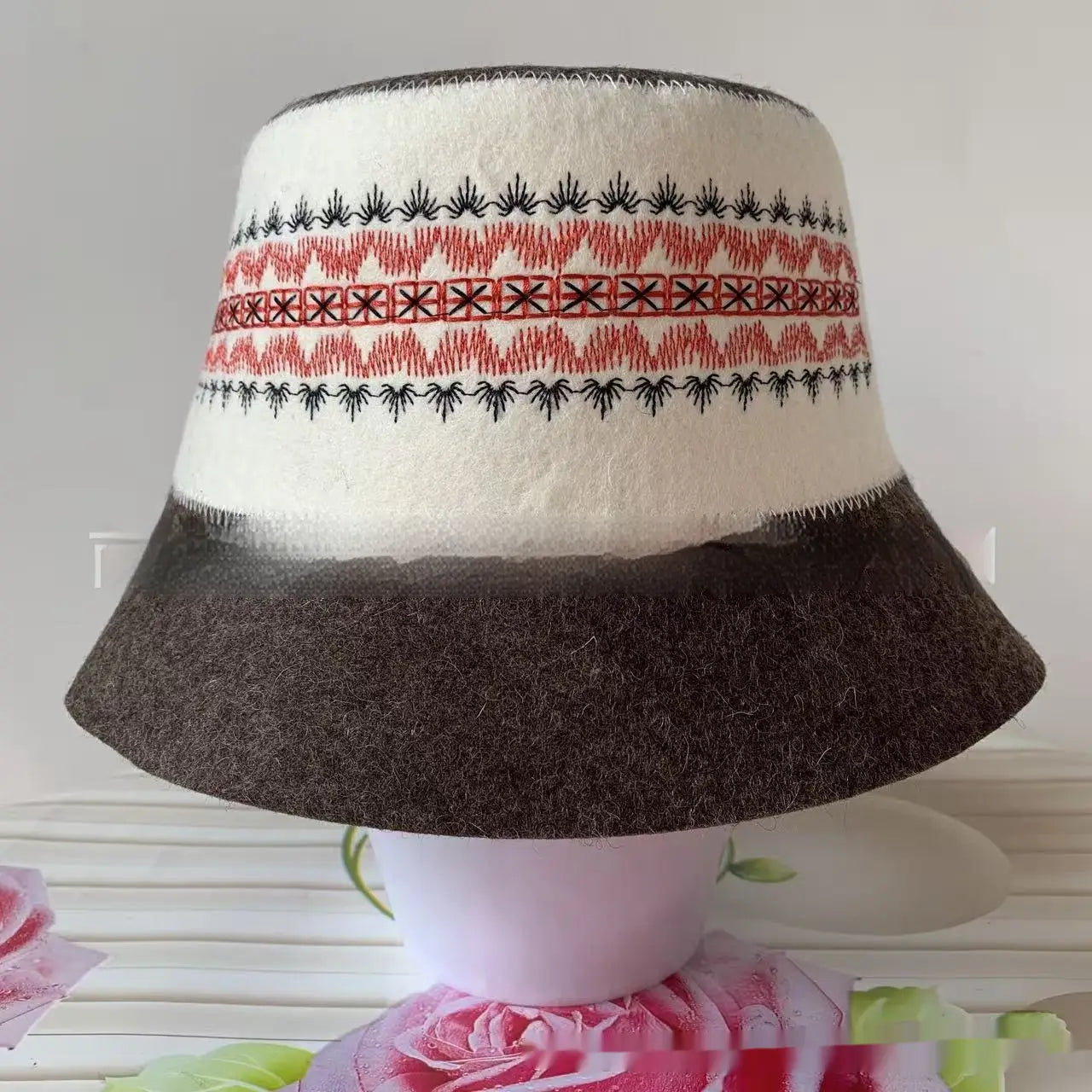 Wool felt sauna cap bucket hat in white and brown featuring intricate red and black embroidered patterns around the crown.