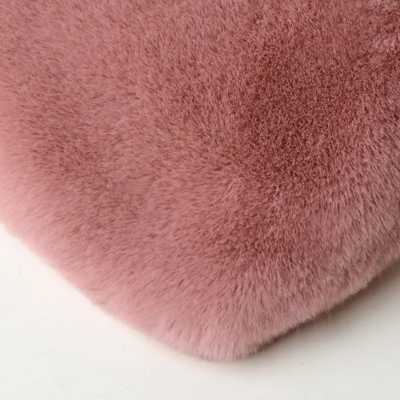 a plush faux fur heart shaped crossbody bag in soft pink with a dense fluffy texture and a gold chain strap