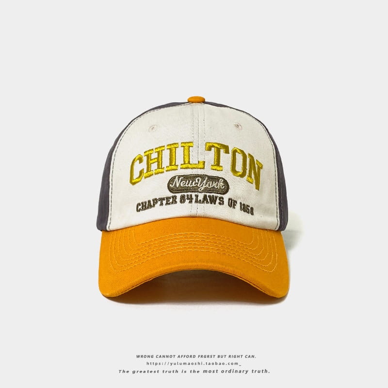 Chapeau de soleil en style vintage, casquette de baseball rétro à empiècements contrastés, avec un panneau avant blanc, des panneaux latéraux gris, et une visière ainsi qu’un bouton orange, avec broderie « Chilton » en lettres jaunes au-dessus d’un écusson ovale noir portant la mention « New York ».