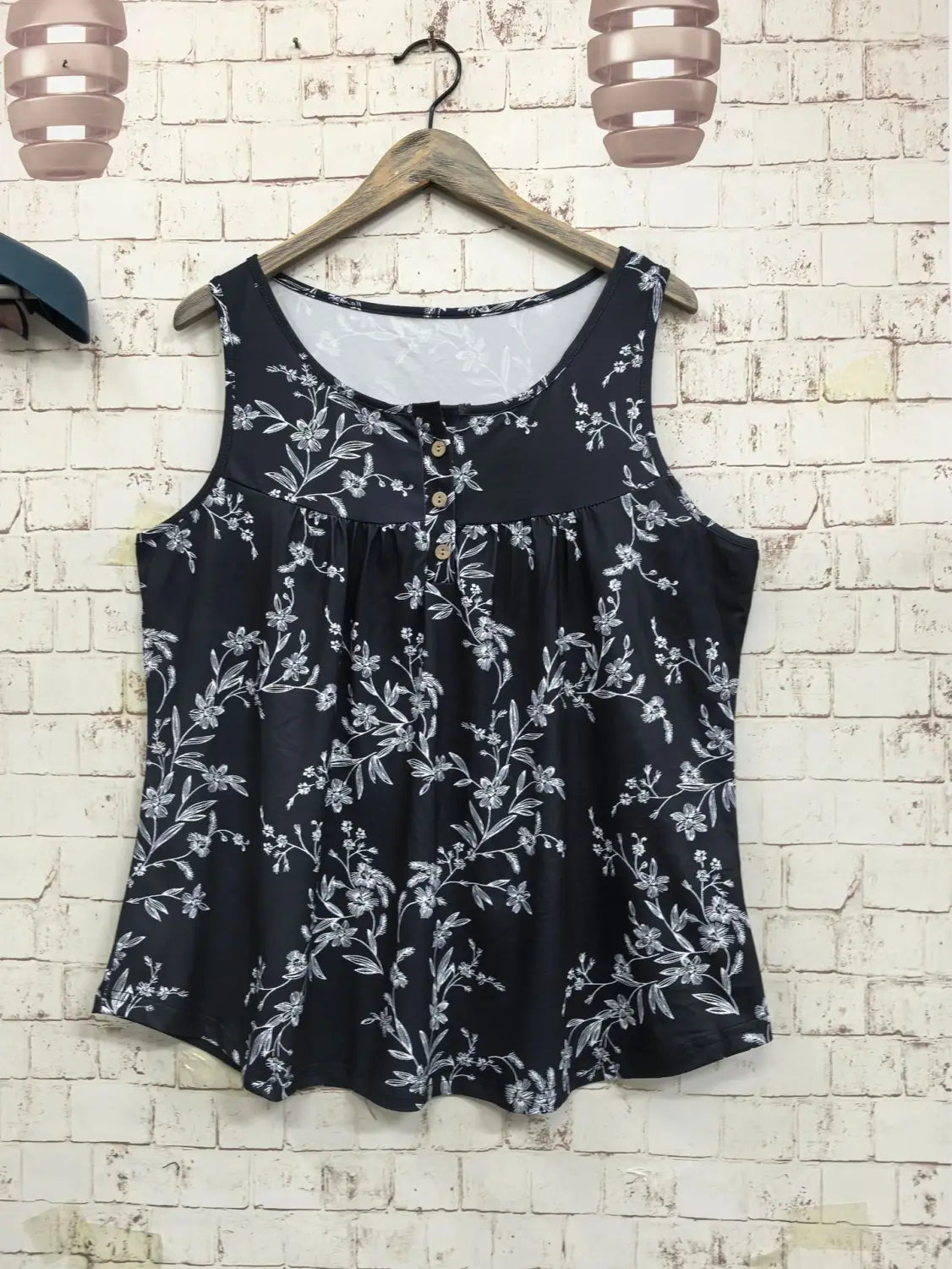 白い刺繍の花と、ノースリーブのデザインをあしらった黒の花柄プリント・ボタン前開きニットキャミソール。