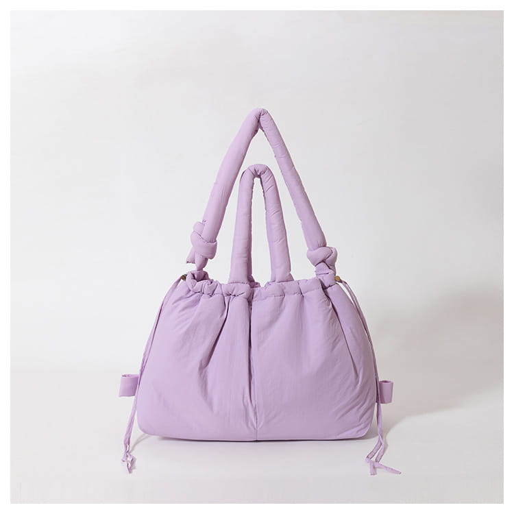 A soft lavender quilted puffer tote bag made of lightweight nylon featuring quilted handles and drawstring ties.