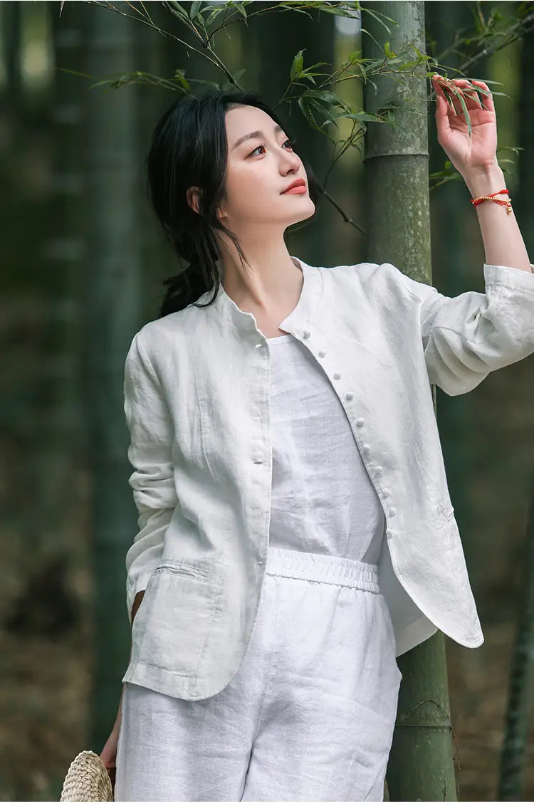 Eine hellgraue Leinen-Patchworkjacke mit relaxedem Schnitt und geknöpfter Vorderseite, mit dezenten Stickdetails.