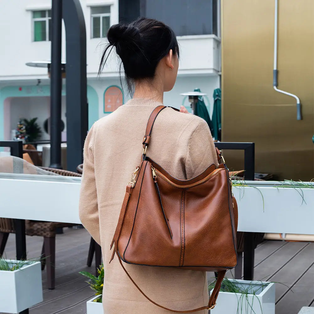 Premium brown leather hobo crossbody bag with gold-tone hardware and a long adjustable shoulder strap.