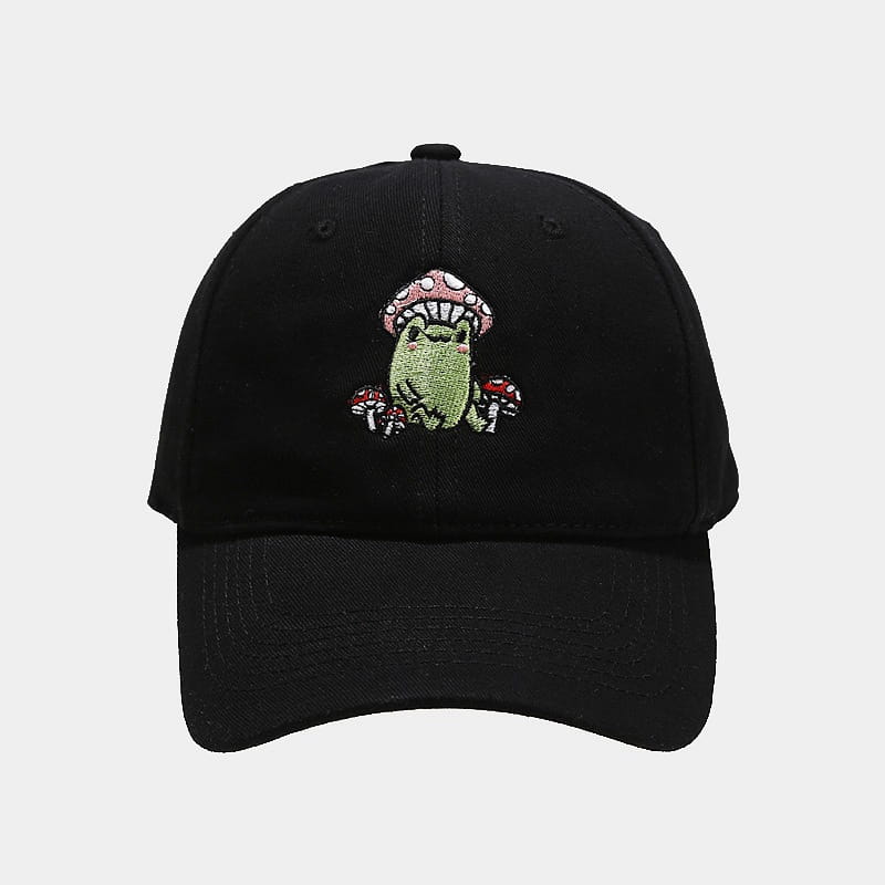 Black baseball cap featuring an embroidered green frog surrounded by pink and red mushrooms on the front panel.