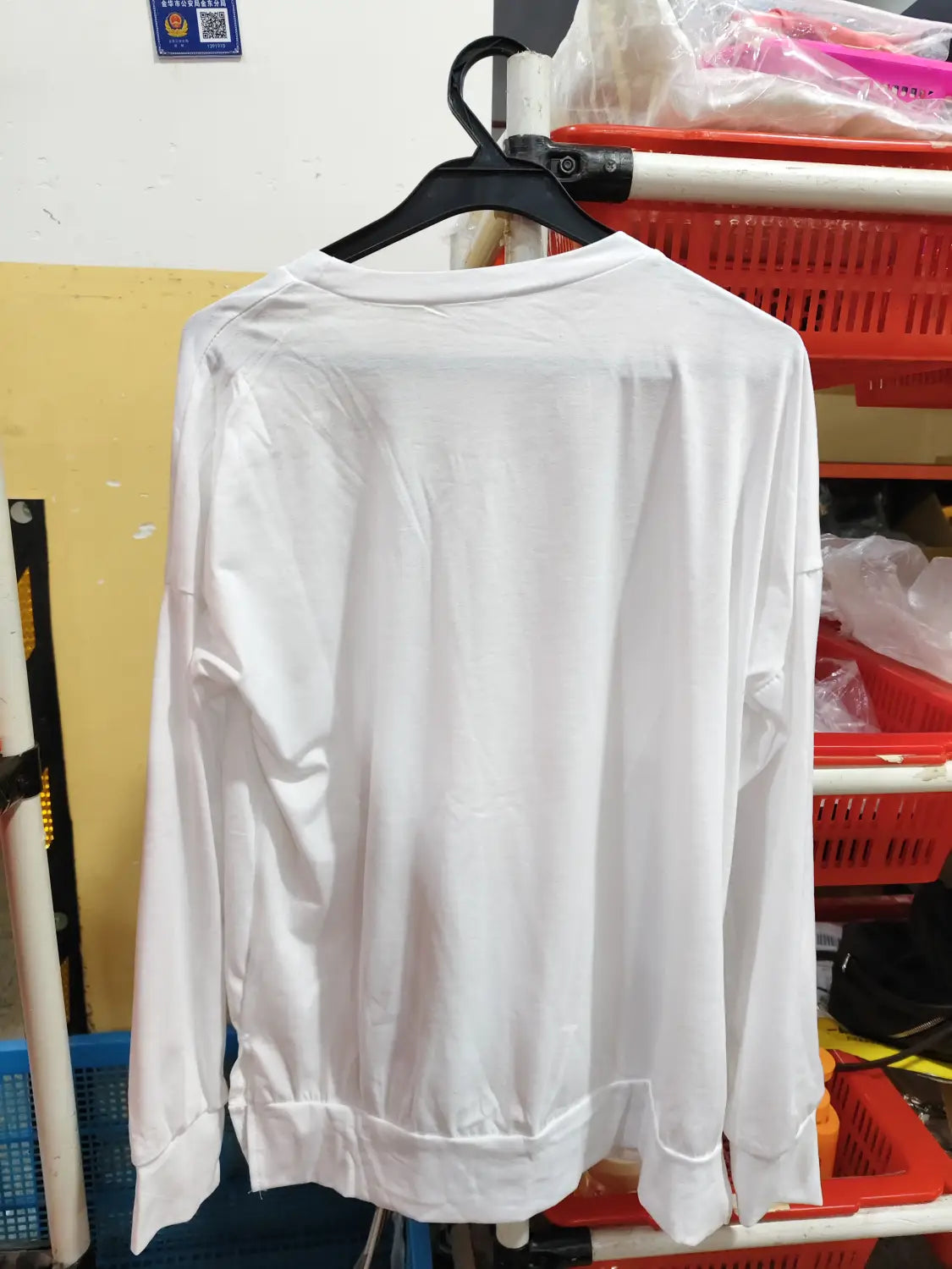 White long-sleeved split front relaxed knit sweater hanging on a black hanger.