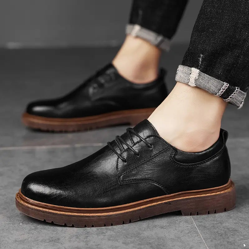 Black leather lace-up oxford shoe with brown rubber sole and stitched detailing for men’s business and casual wear.