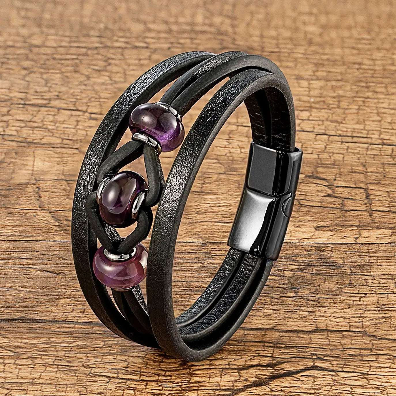 Bracelet en cuir noir à cordon, avec trois perles en pierre naturelle violettes et une fermeture magnétique.