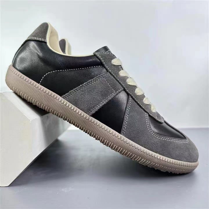 Schwarze und graue Veloursleder-Ledersneaker mit beigen Schnürsenkeln und einer strukturierten Gummisohle, ausgelegt als vielseitige Freizeitschuhe im Low-Top-Design.