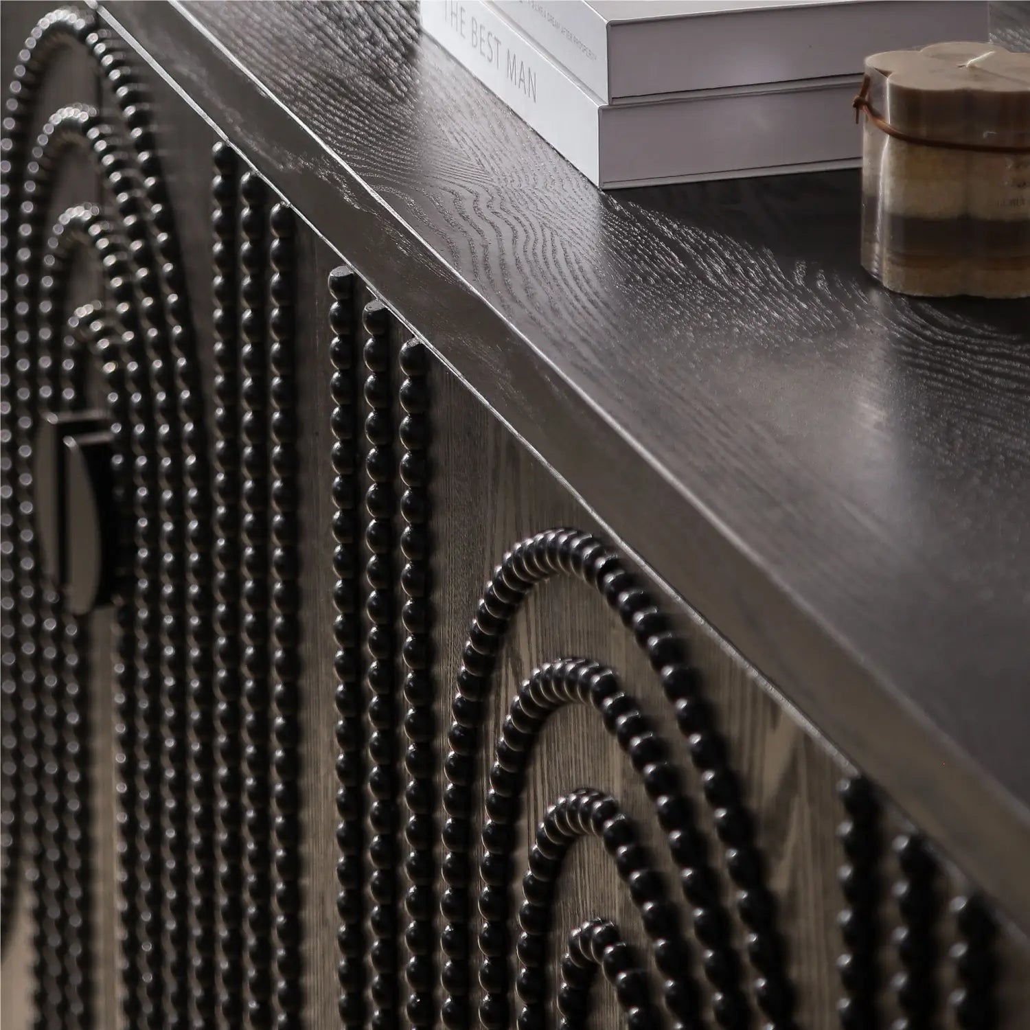 Schwarzes Sideboard-Schrankmöbel mit gebogenen Nagelkopfreißern als Akzent, mit einer schwarzen Perbenseite, dunkler Holzoberfläche und geschwungenen, konzentrischen Perb Mustern.