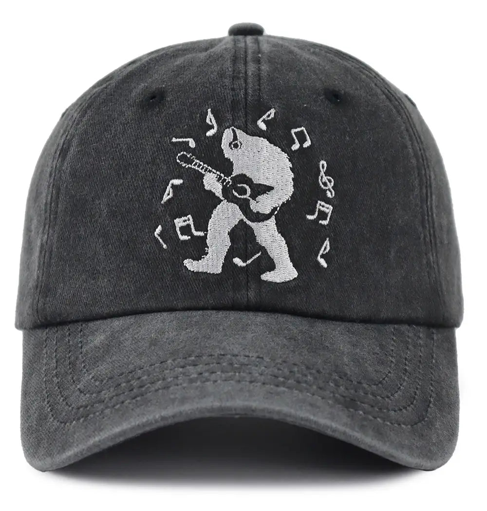 A dark gray distressed cotton baseball cap featuring a white embroidered design of bigfoot playing an acoustic guitar surrounded by musical notes.