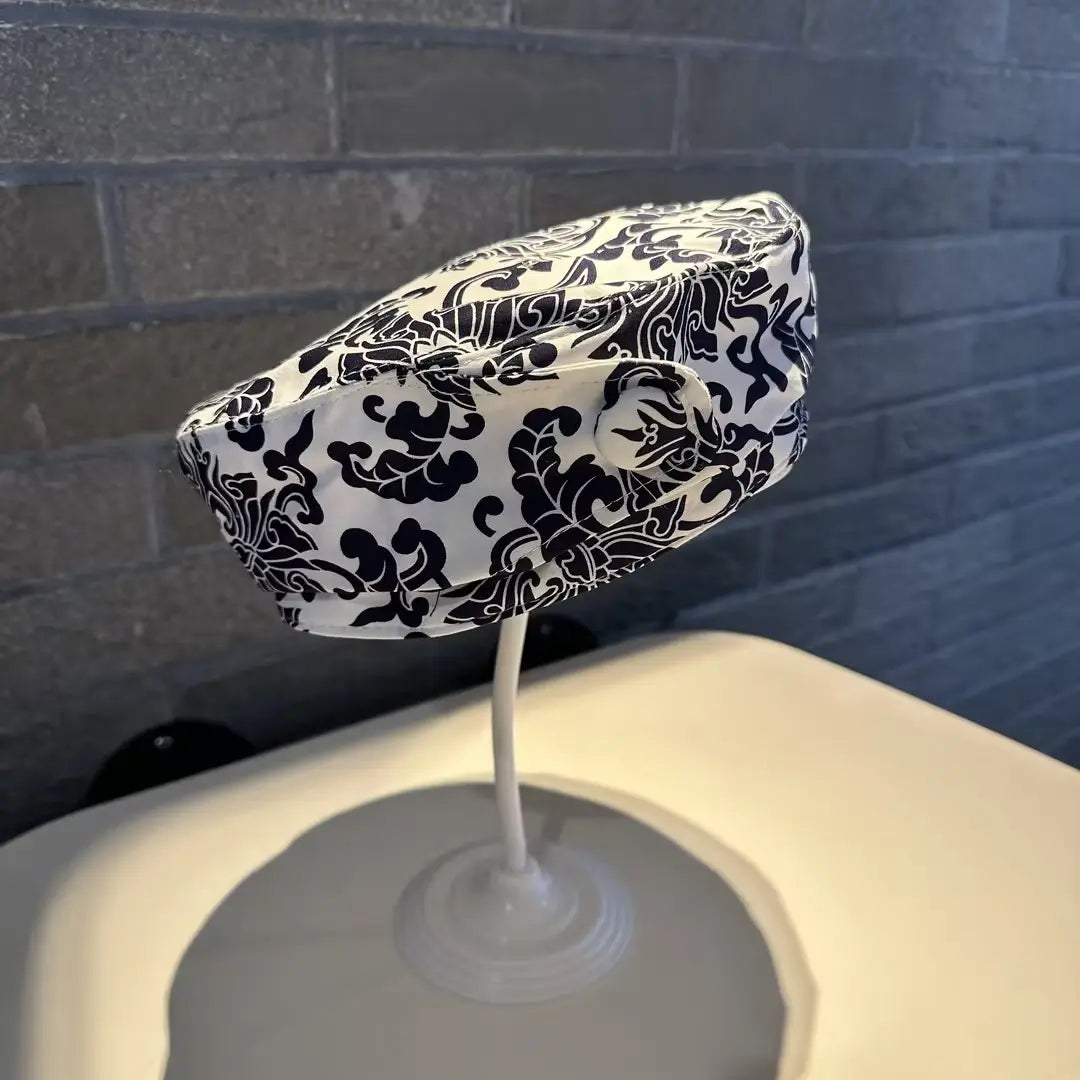 printed korean style fashion cap displayed on a stand featuring black and white damask-patterned fabric
