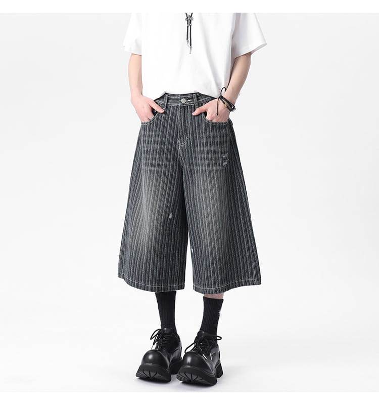 Striped denim capri shorts featuring black and white vertically striped wide-leg design with a distressed faded finish.