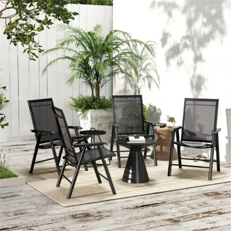 Chaises de patio pliantes d’extérieur, lot de 4, pour un aménagement de patio avec assises en maille, présentant des chaises en maille noire avec des cadres métalliques élégants disposés autour d’une table d’appoint latérale conique noire assortie.