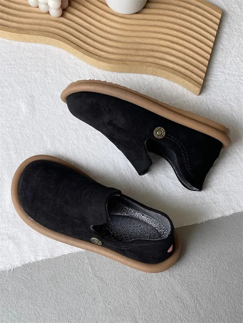 Schwarze Veloursleder-Slipper im Vintage-British-Stil mit niedrigem Absatz mit einer braun wirkenden Gummisohle und kleinen metallisch wirkenden Knopfakzenten