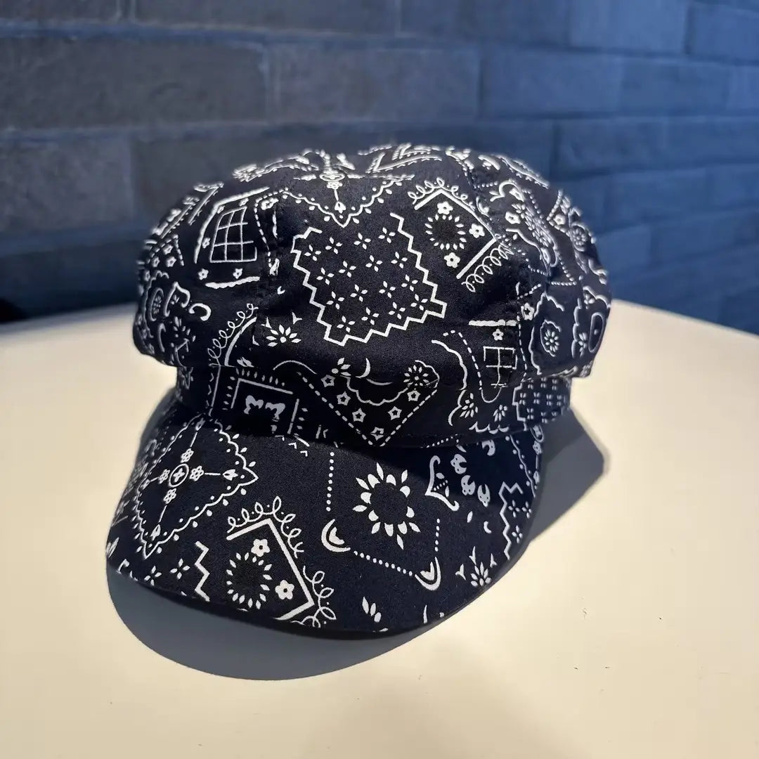 Floral newsboy cap for women made of black fabric with white bandana-patterned geometric and floral designs.