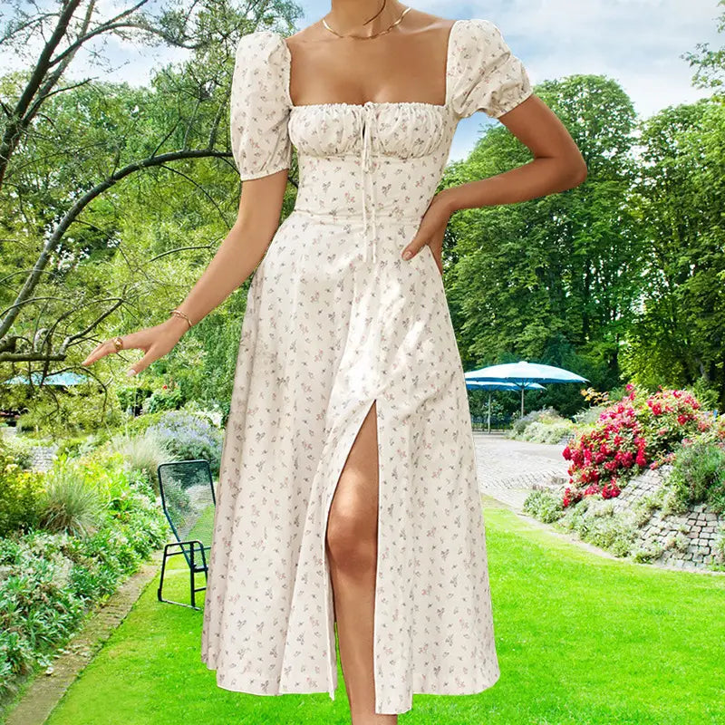 A woman wearing an off-white floral print midi dress with puffed short sleeves, a square neckline, and a slit, suitable for elegant occasions.