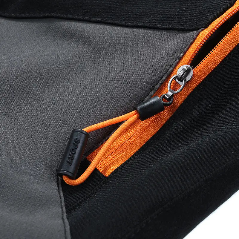 Black and orange zipper pull with a black plastic sport tag on men waterproof hiking pants stretch tactical trousers.