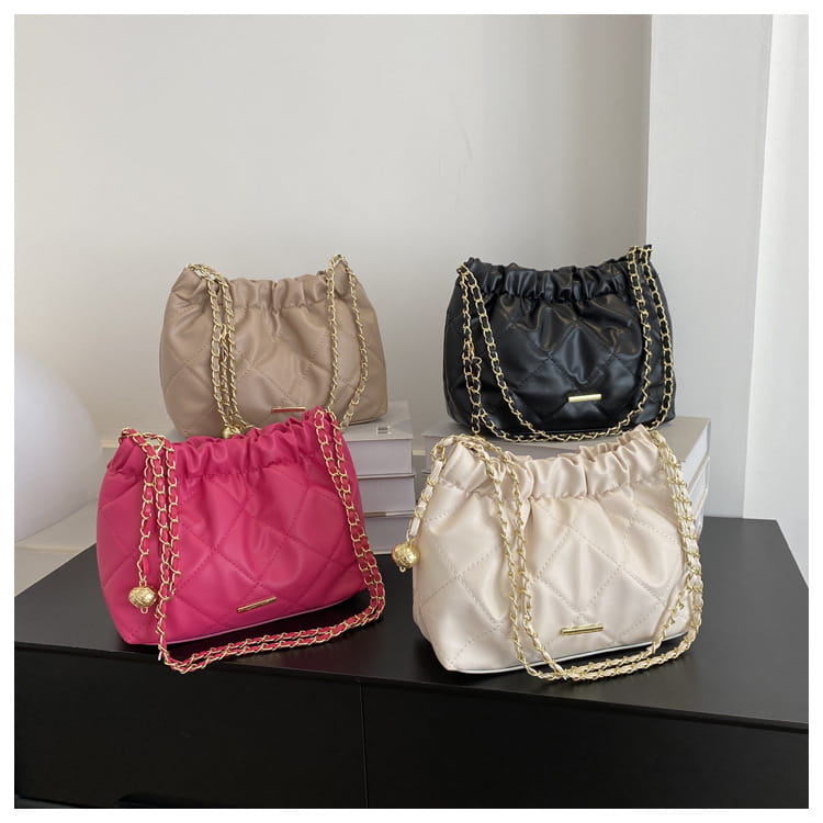 A vibrant pink quilted faux leather crossbody bag with a gold chain strap and decorative tassel.